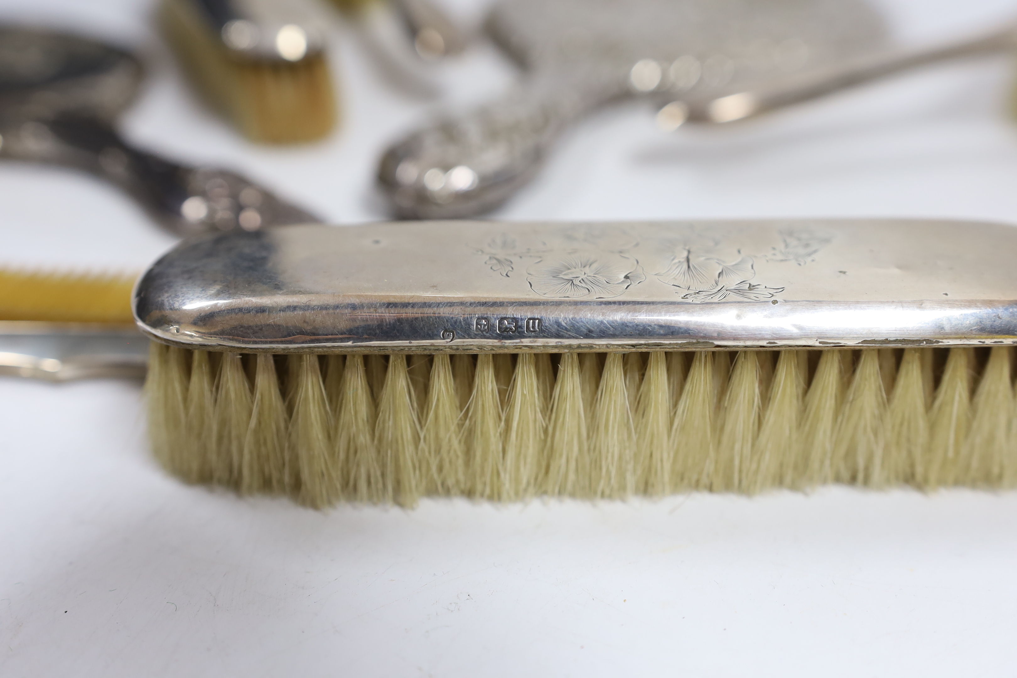Two early 20th century repousse silver mounted hand mirrors with Reynold's Angels decoration, four silver mounted brushes and a comb.